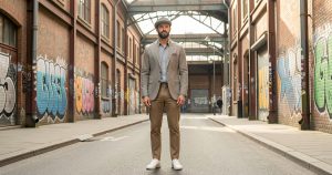 Homme portant une tenue chic décontractée et une casquette dans un quartier urbain de Saint-Étienne.